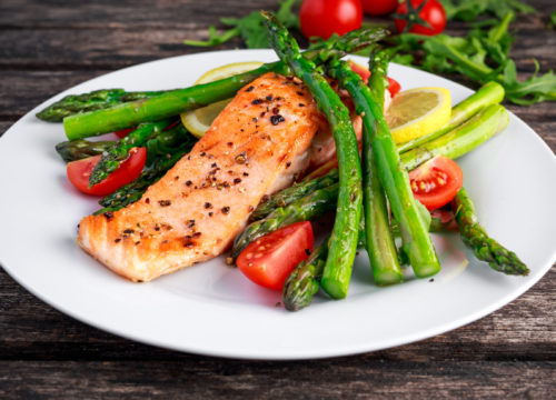 A plate of Salmon, asparagus, and tomatoes.