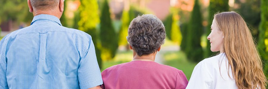 Elderly couple walking in the nature with the carer